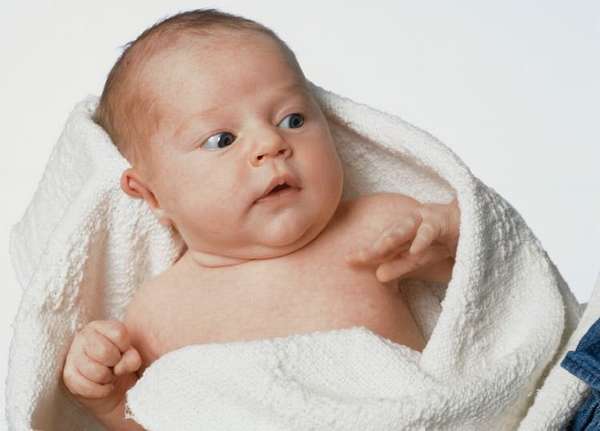 Заканчиваем купание новорожденного ребенка, завернув его в мягкое полотенце.